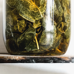 Glass jar with green leafy contents on a marble surface