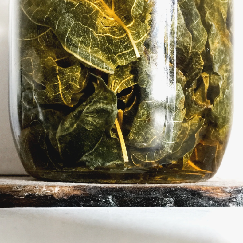 Glass jar with green leafy contents on a marble surface